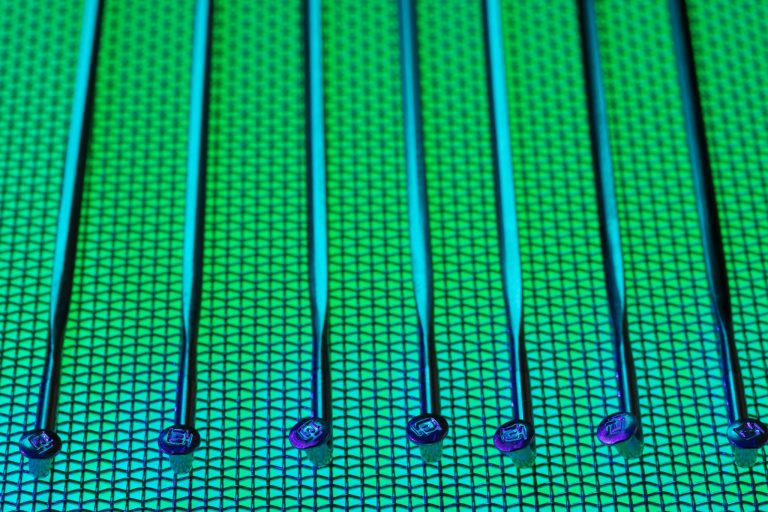 Vivid and detailed close-up of a patterned silicon wafer with vibrant green and blue colors.